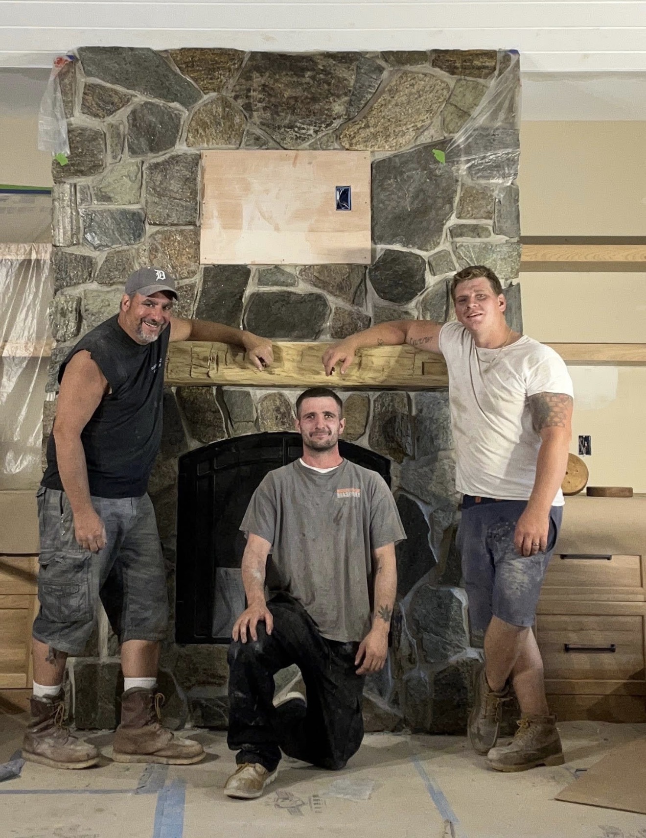 Paramount Masonry LLC crew in front of a finished stone fireplace build